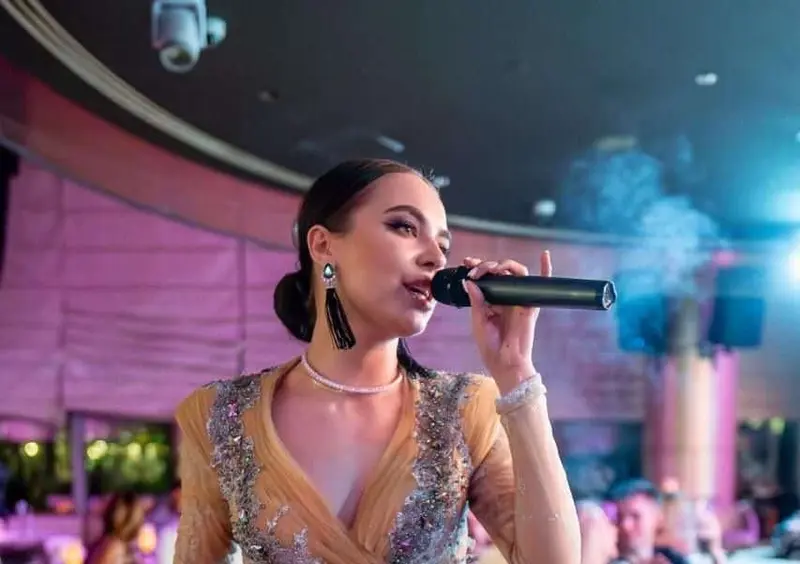 Singer in a sequinned gown singing to diners in a restaurant lounge